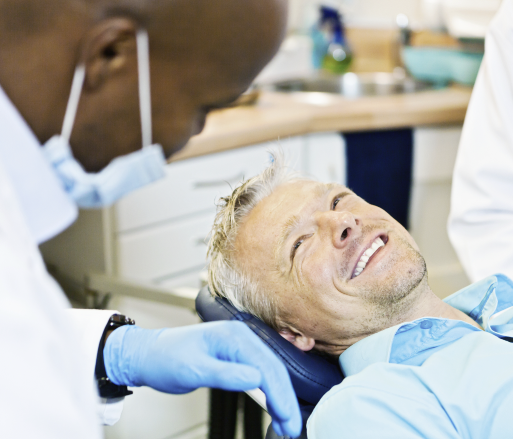 Male patient in the dentist’s chair smiling at the dentist